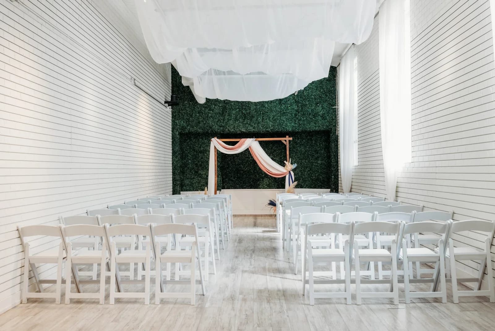 Gather's indoor hall arranged with rows of white chairs and a ceremony arch.
